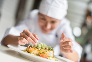 Chef decorating a plate in the kitchen of a restaurant - focus on foreground